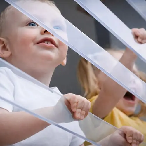 Děti hledící skrz průhledné ochranné mříže KENEX